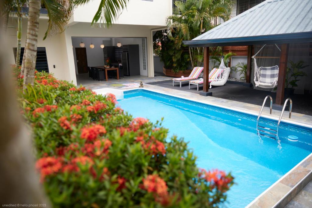 a swimming pool with chairs and flowers next to a house at Tropical Villa Rainville in Paramaribo