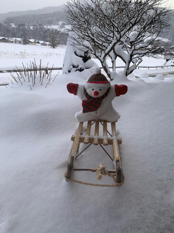 a stuffed snowman sitting on a sled in the snow at Ferienhaus Haas inkl. Chiemgaukarte in Ruhpolding