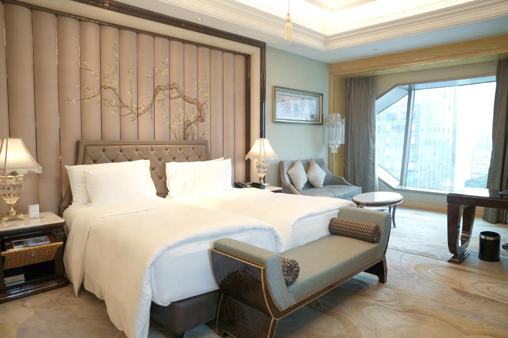a bedroom with a large white bed and a chair at Wanda Reign Wuhan in Wuhan