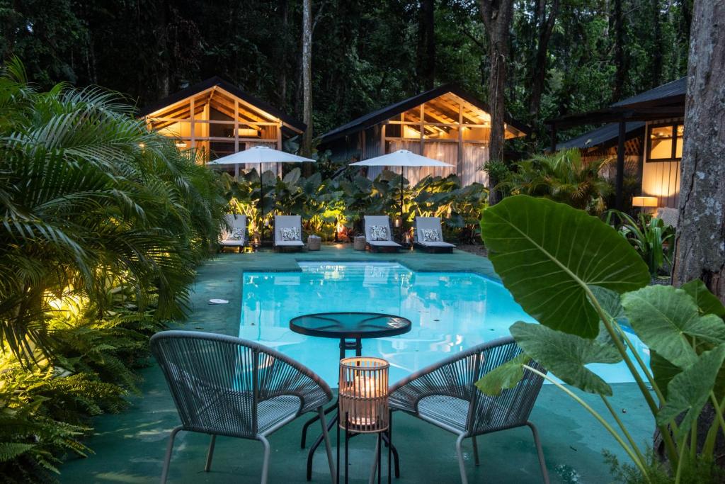 una mesa y sillas junto a una piscina por la noche en KAÑIK APART HOTEL, en Puerto Viejo