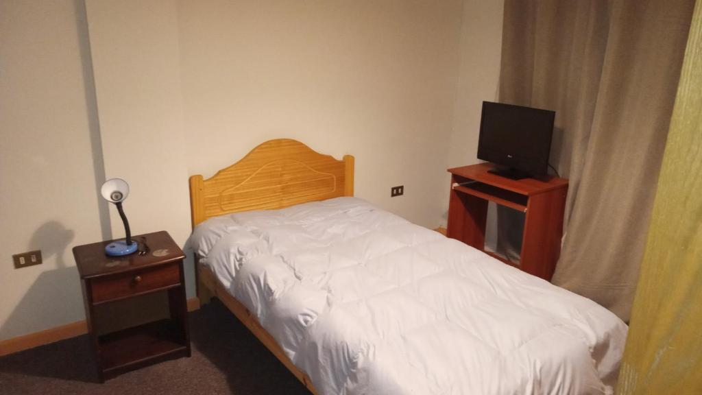 Dormitorio pequeño con cama y TV en Habitancion disponible en Vallenar