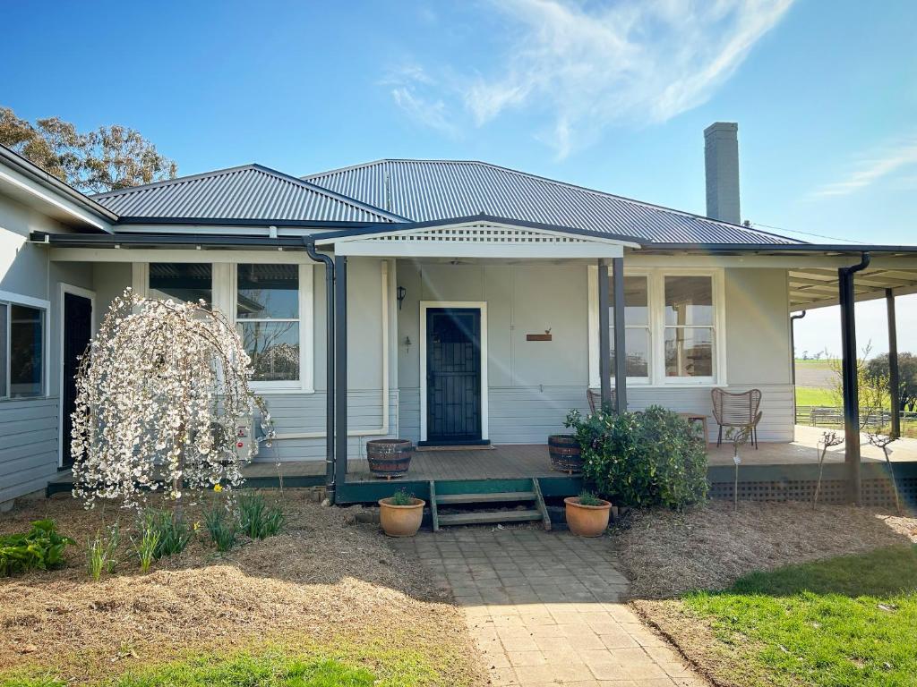 una casa blanca con un banco en el patio en Linden Cottage Farm Stay, en Harden