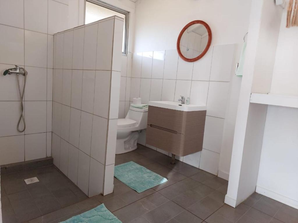 a bathroom with a sink and a toilet and a mirror at Cabañas Kitai in Hanga Roa