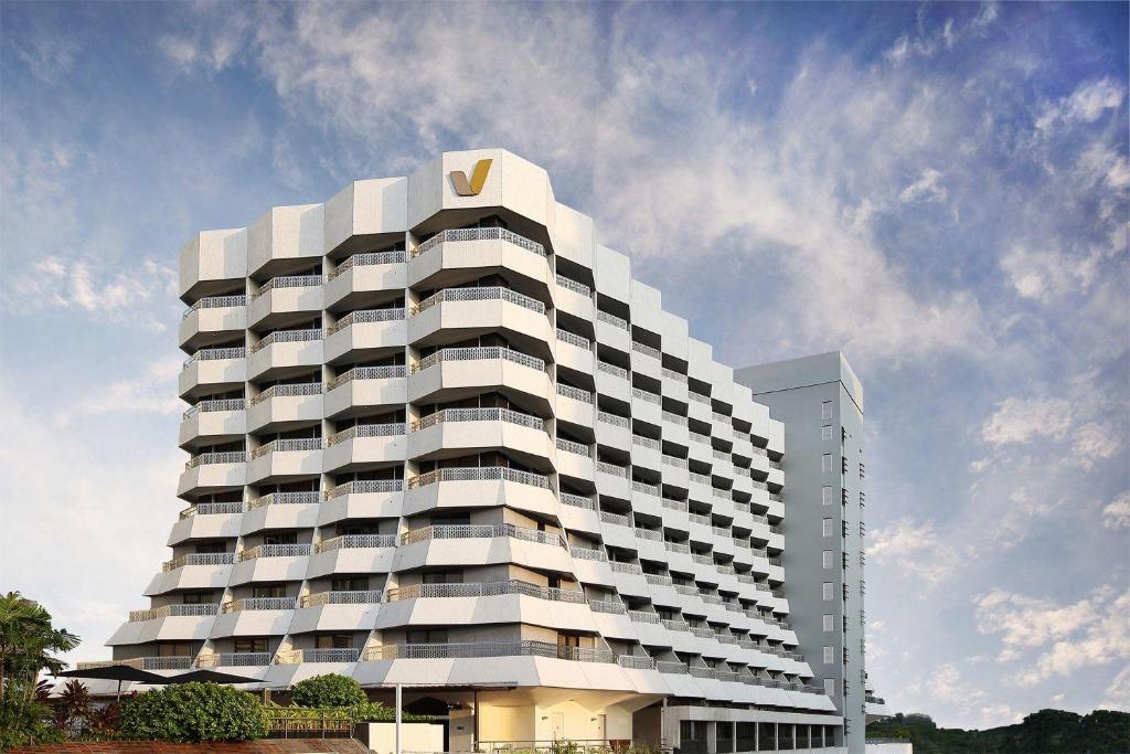 ein hohes weißes Gebäude mit einem goldenen Logo darauf in der Unterkunft Village Hotel Katong by Far East Hospitality in Singapur