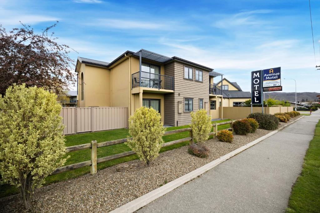 une maison avec une clôture et des arbres devant elle dans l'établissement Avenue Motel, à Alexandra