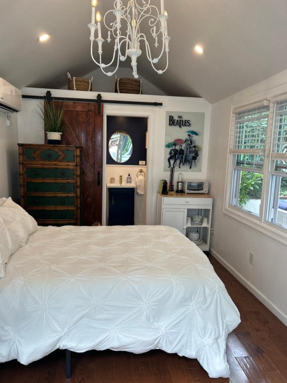 een slaapkamer met een groot wit bed en een kroonluchter bij Adorable 1 bedroom cottage in Forest Hills