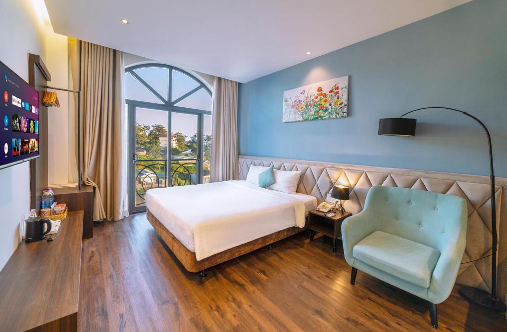 um quarto de hotel com uma cama e uma cadeira em Stillus Boutique Dalat Hotel em Da Lat