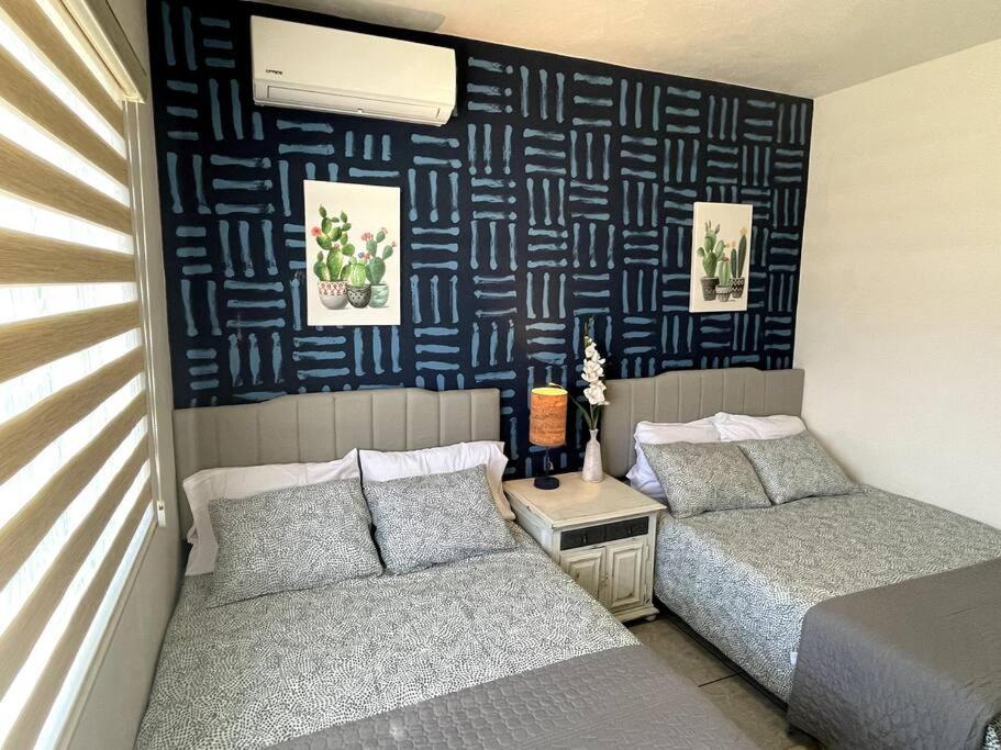 1 dormitorio con 2 camas y pared azul en El Depa de las Flores-300 m from the main blvd en San Carlos