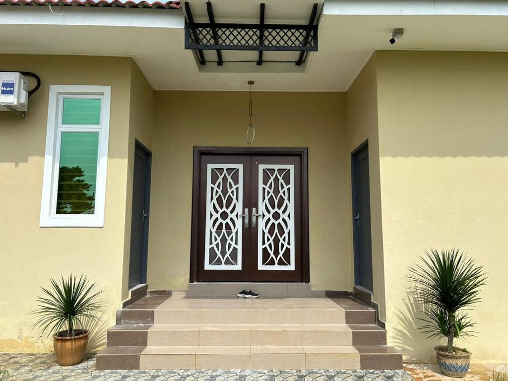 une porte d'entrée d'une maison avec deux plantes dans l'établissement Aurora Roomstay, à Kota Bharu
