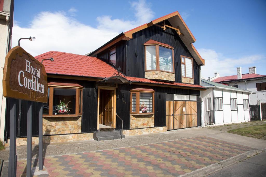 un edificio blanco y negro con techo rojo en Hostal Cordillera, en Punta Arenas