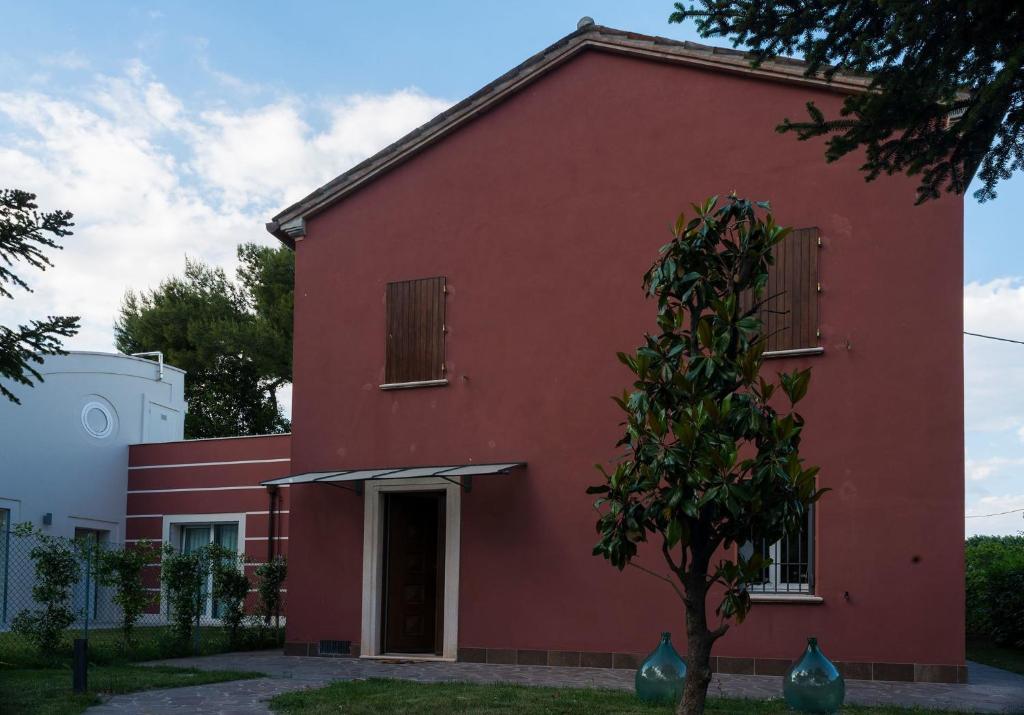 un edificio rosso con un albero di fronte di Casale Simbeni a Misano Adriatico