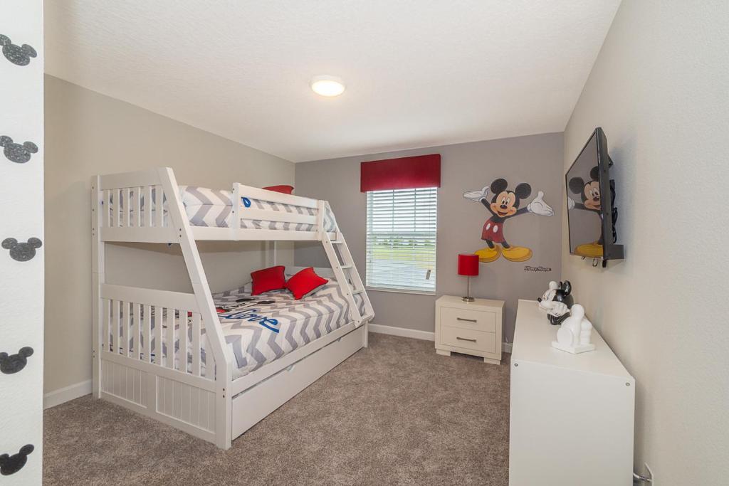 a bedroom with a bunk bed with mickey mouse on the wall at Luxury Townhouses 18 Minutes away from Disney! in Kissimmee
