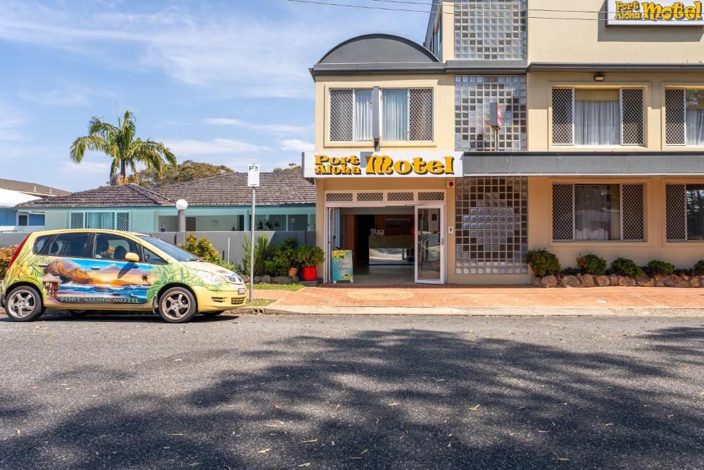 una piccola auto parcheggiata di fronte a un edificio di Port Aloha Motel a Port Macquarie