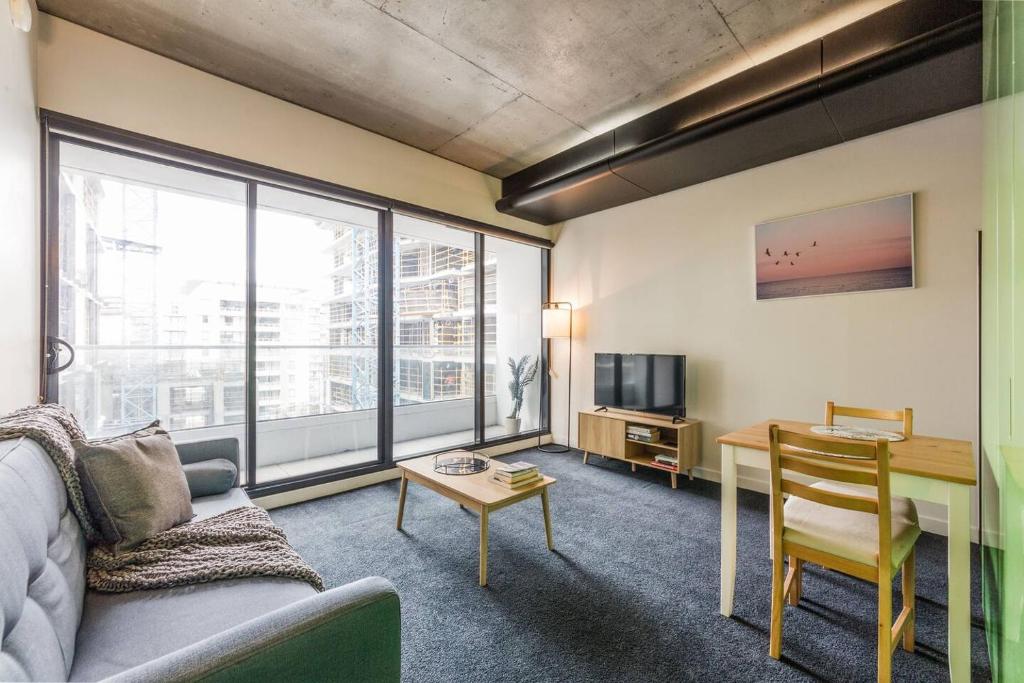 sala de estar con sofá, mesa y escritorio en Vibrant Inner-City Living with Luxe Rooftop Pool, en Melbourne