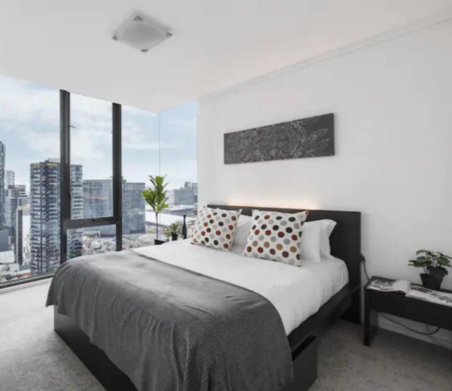 een slaapkamer met een groot bed en een groot raam bij Cradle the Clouds - Southbank Stay with Parking in Melbourne