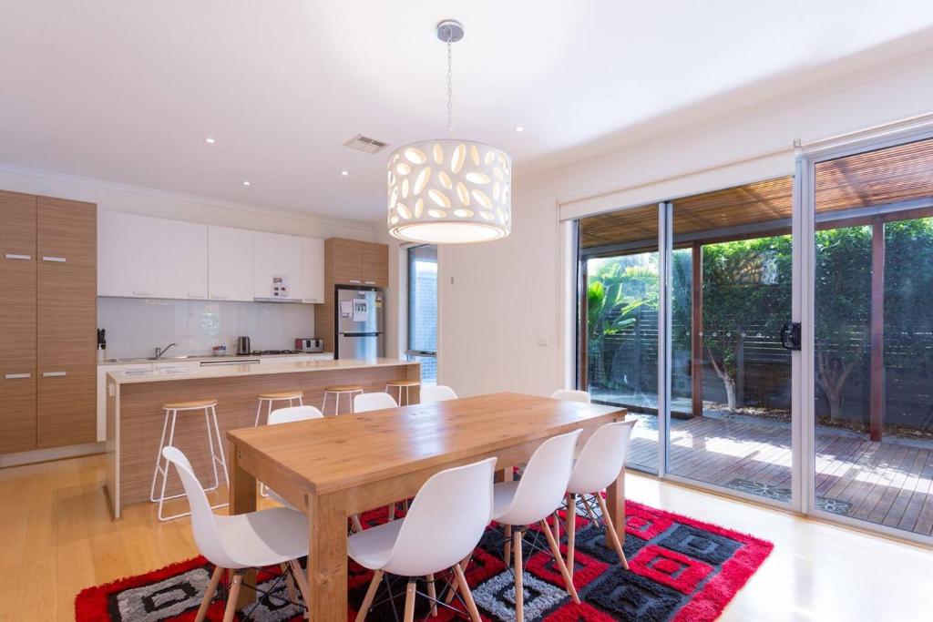 a kitchen and dining room with a wooden table and chairs at Leafy Family Home with Outdoor Dining near CBD in Maribyrnong