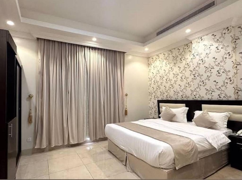 a bedroom with a large bed and a large window at الجوهرة البيضاء للشقق المخدومة in Jeddah