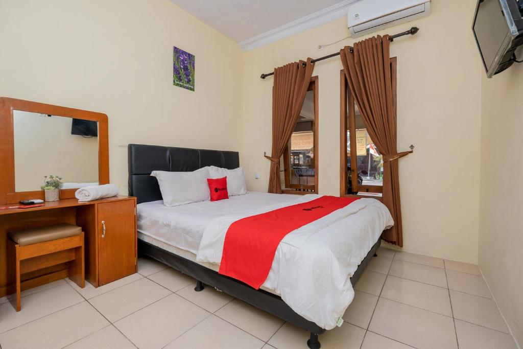 a bedroom with a bed and a desk and a television at RedDoorz Syariah At Danau Maninjau Sawojajar in Malang