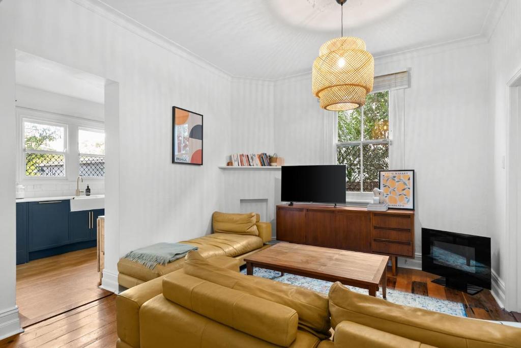 ein Wohnzimmer mit einem Sofa und einem Tisch in der Unterkunft Pocket of Petersham - A Stylish Inner-West Retreat in Sydney