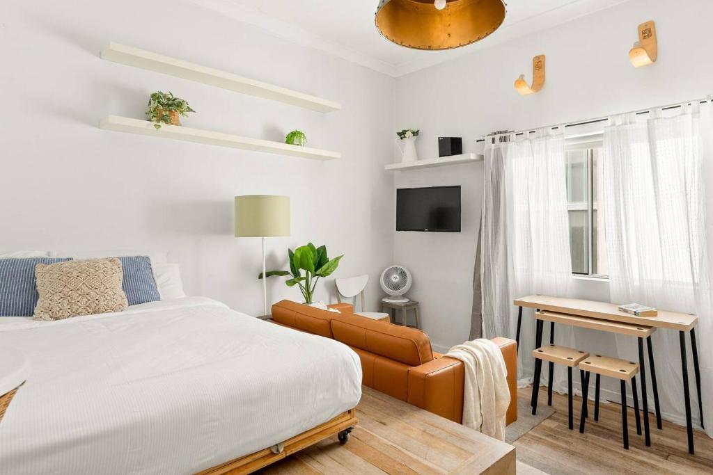 a white bedroom with a bed and a couch at A Cosy Scandi-Style Studio on Bondi Beach in Sydney