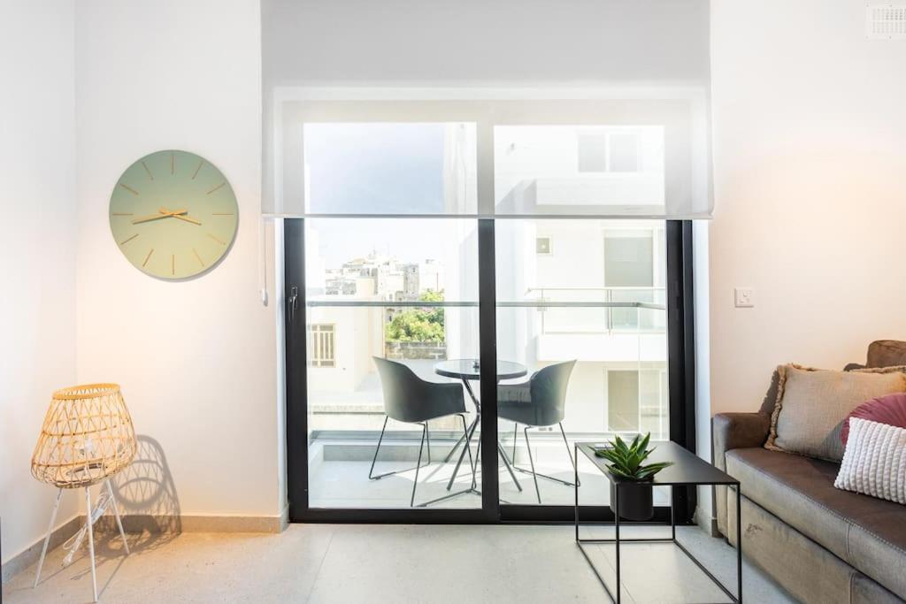 een woonkamer met een tafel en een klok aan de muur bij Sliema Boutique Apartments in Sliema