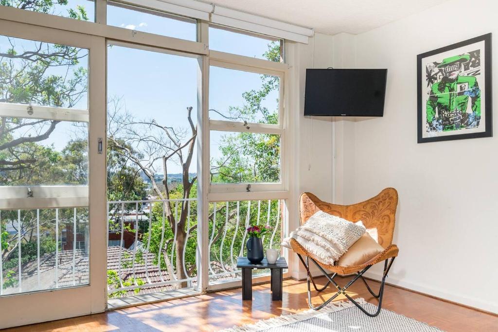 sala de estar con silla y ventana grande en Leafy Paddington Studio with Harbour Views en Sídney
