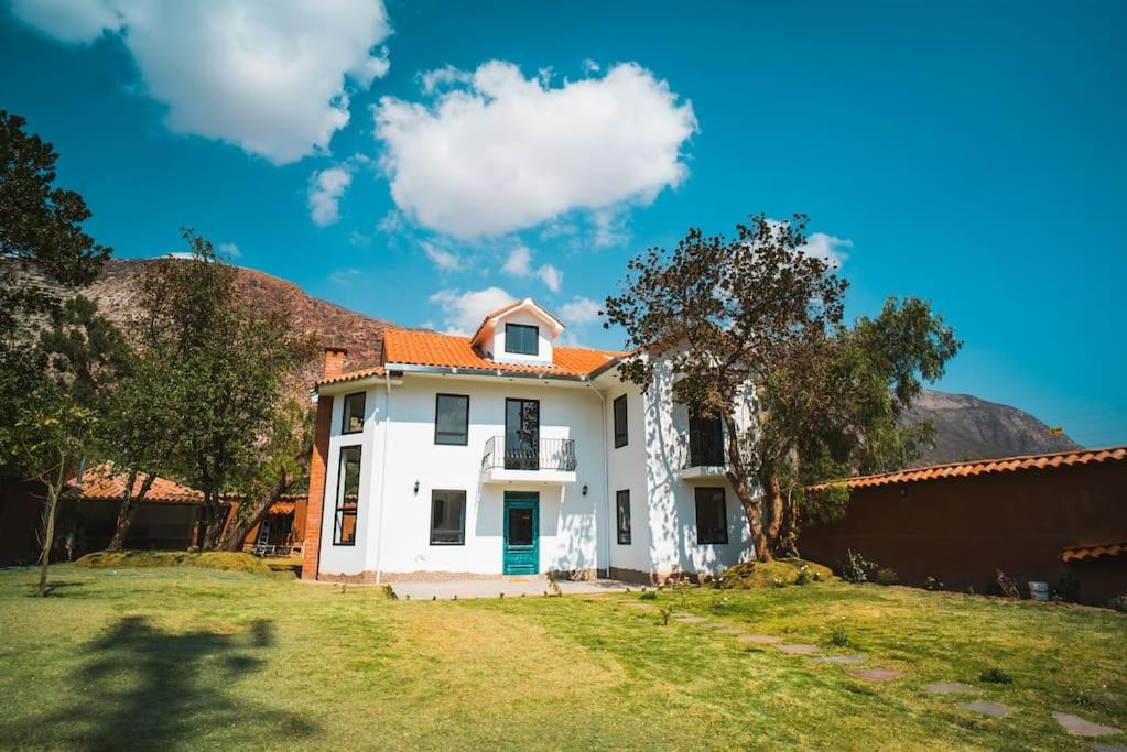 a white house with an orange roof in a yard at Beautiful house in the Sacred Valley "Casa Julia Cusco" in Cusco