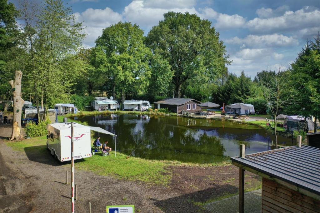a rv parked next to a lake with houses at Het Denneke in Veldhoven