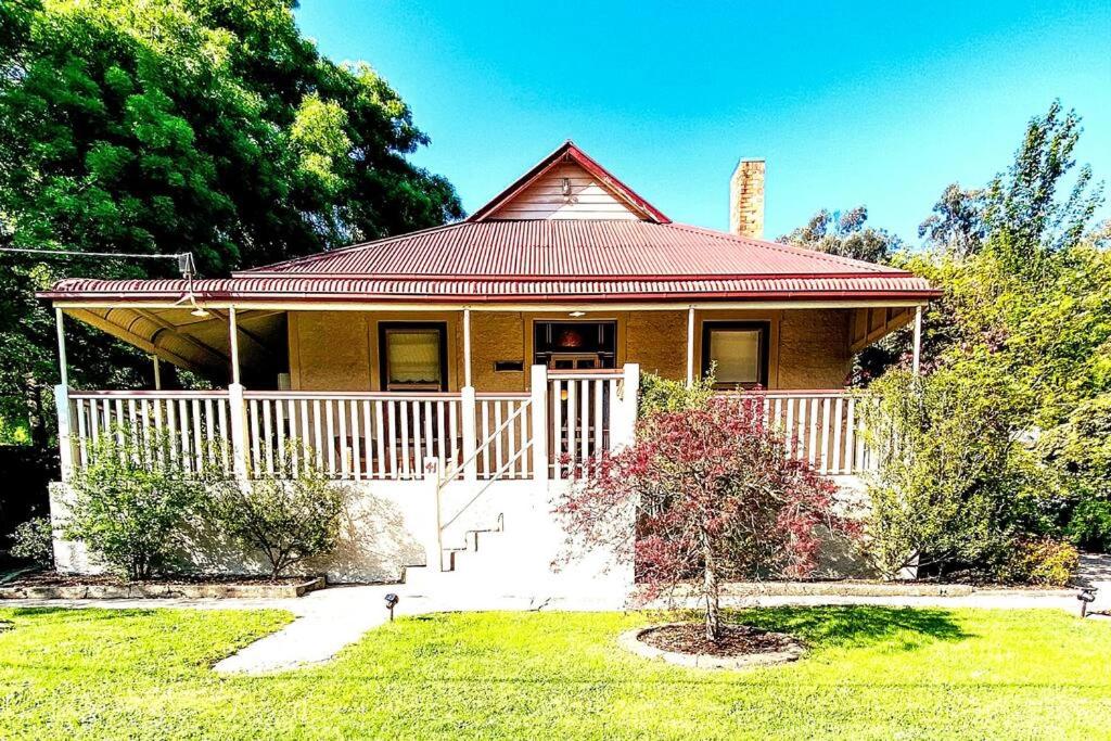 a small yellow house with a red roof at Carinya Cottage in Myrtleford