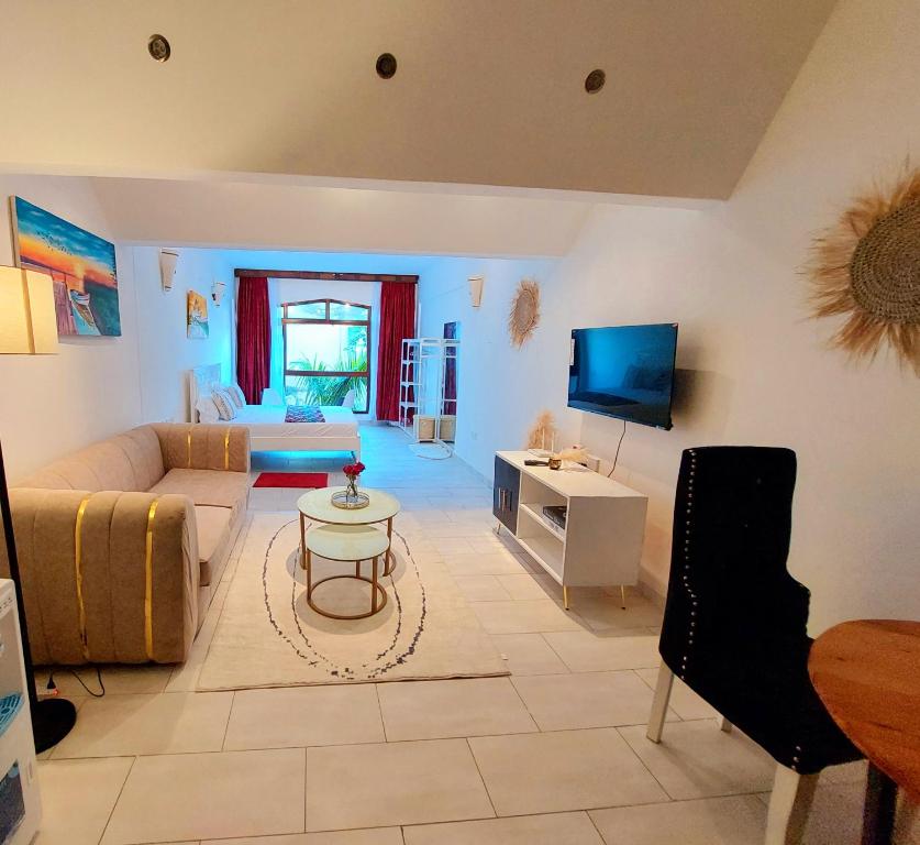 een woonkamer met een bank en een tv bij Slique Apartment in Ukunda