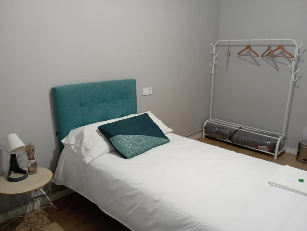 a bedroom with a white bed with a blue headboard at Ecorooms PADRÓN in Padrón