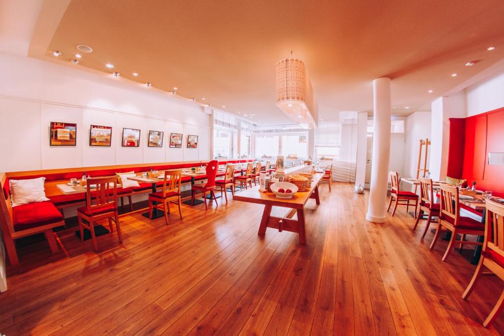 a dining room with wooden tables and red chairs at Hotel Zum Ochsen in Oberstenfeld