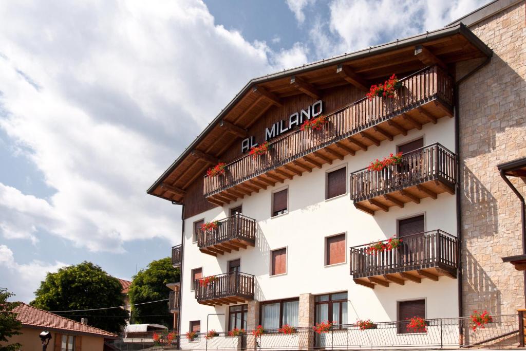 ein weißes Gebäude mit Balkonen und Blumen darauf in der Unterkunft Albergo Milano in Bossico