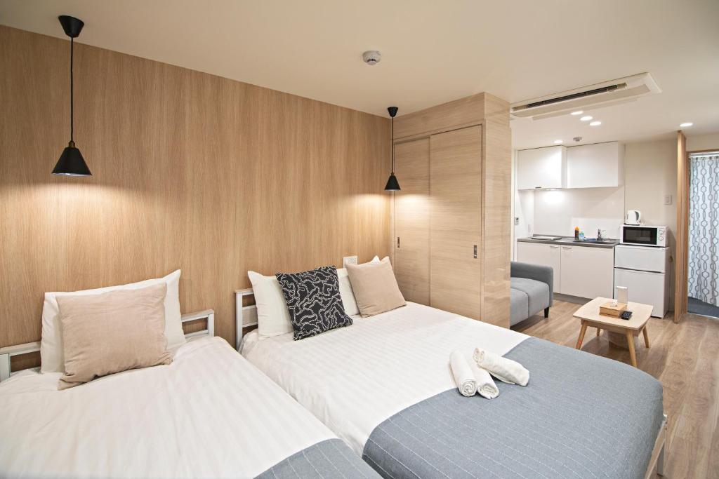 ein Hotelzimmer mit 2 Betten und einer Küche in der Unterkunft 拾野の家 101洋室 in Osaka