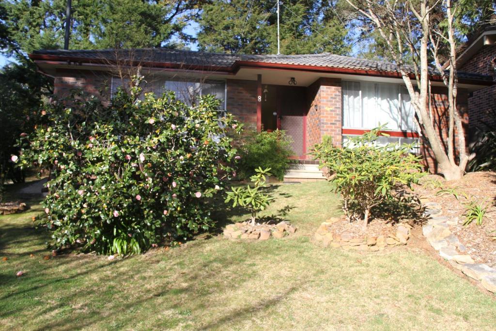 a house with a flowering bush in the yard at Azalea Cottage, Leura NSW Australia in Leura