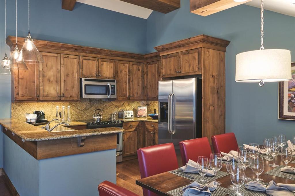 a kitchen with wooden cabinets and a table with red chairs at The Sebastian, Vail Village in Vail