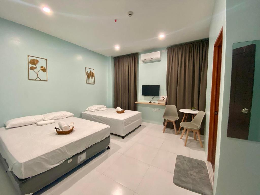a bedroom with two beds and a table and a desk at Torres Traveller's Inn 