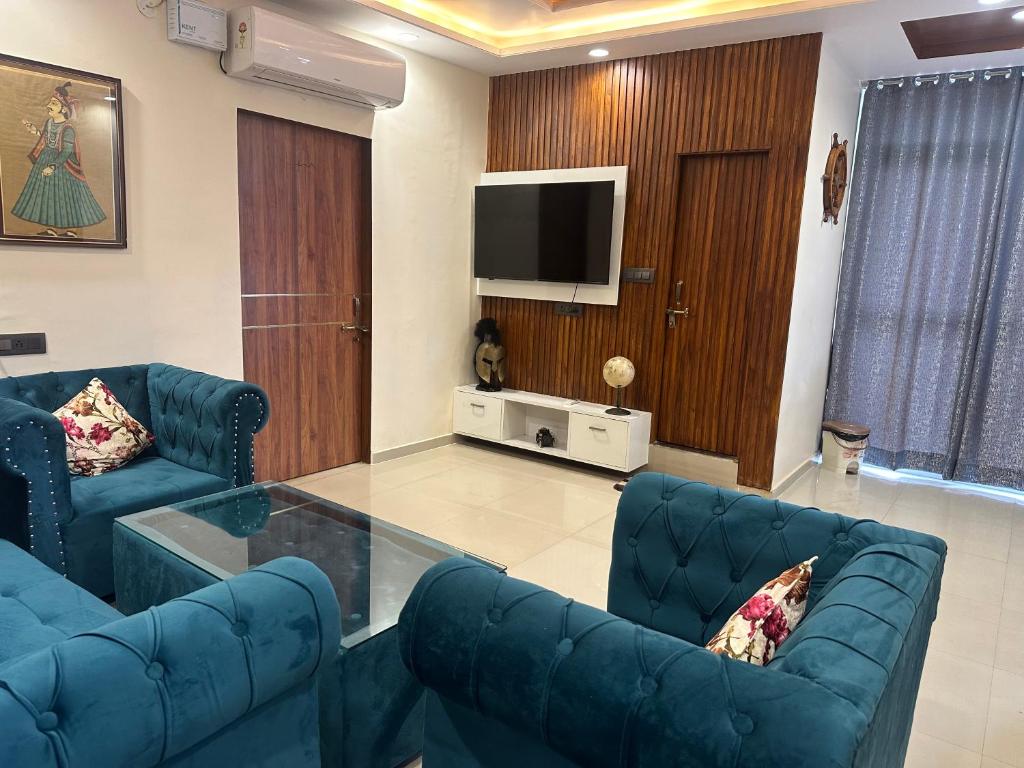 uma sala de estar com dois sofás azuis e uma televisão em UP TOWN JAIPUR em Jaipur