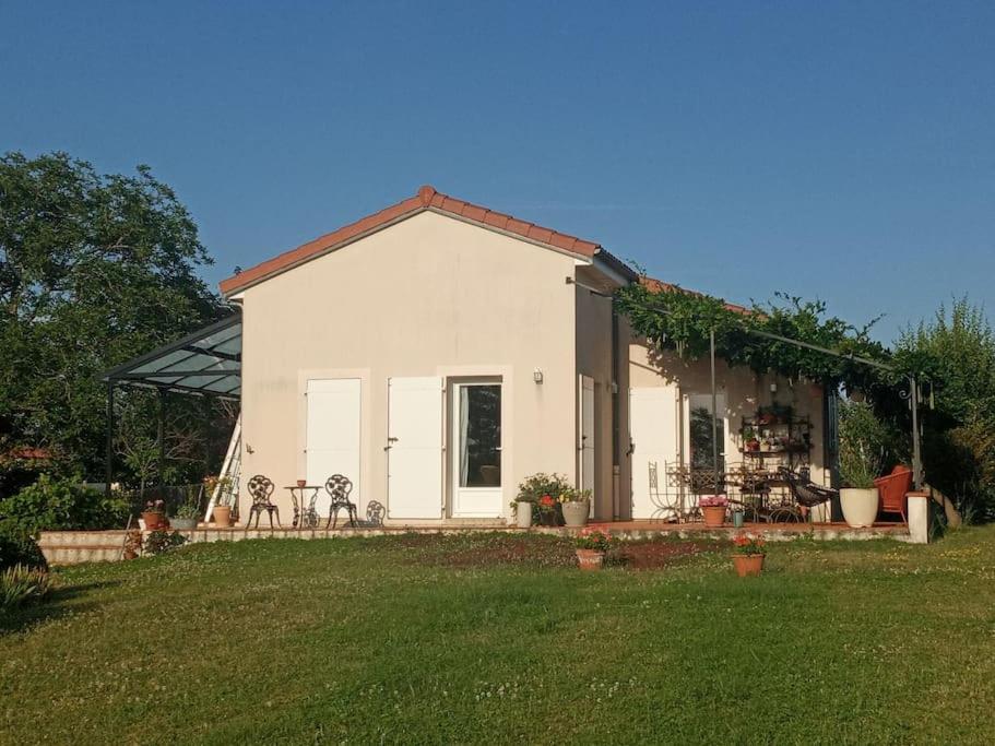 ein kleines weißes Haus mit einem Rasenhof in der Unterkunft Maison à la campagne idéalement située dans le 63 in Beauregard-lʼÉvêque