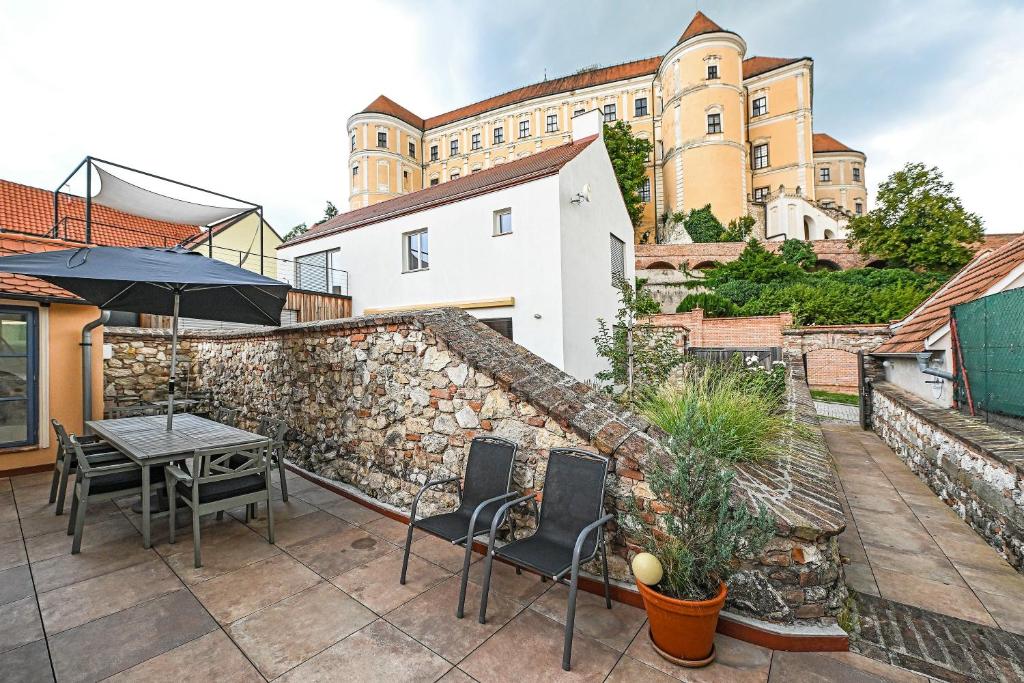 a patio with a table and chairs and a stone wall at Boutique Apartman Mikulov in Mikulov