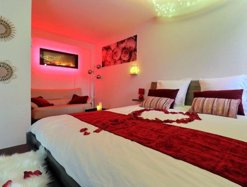 1 dormitorio con 1 cama grande con iluminación roja en Nuit Romantique avec Jacuzzi à 15 min de Toulouse en Blagnac