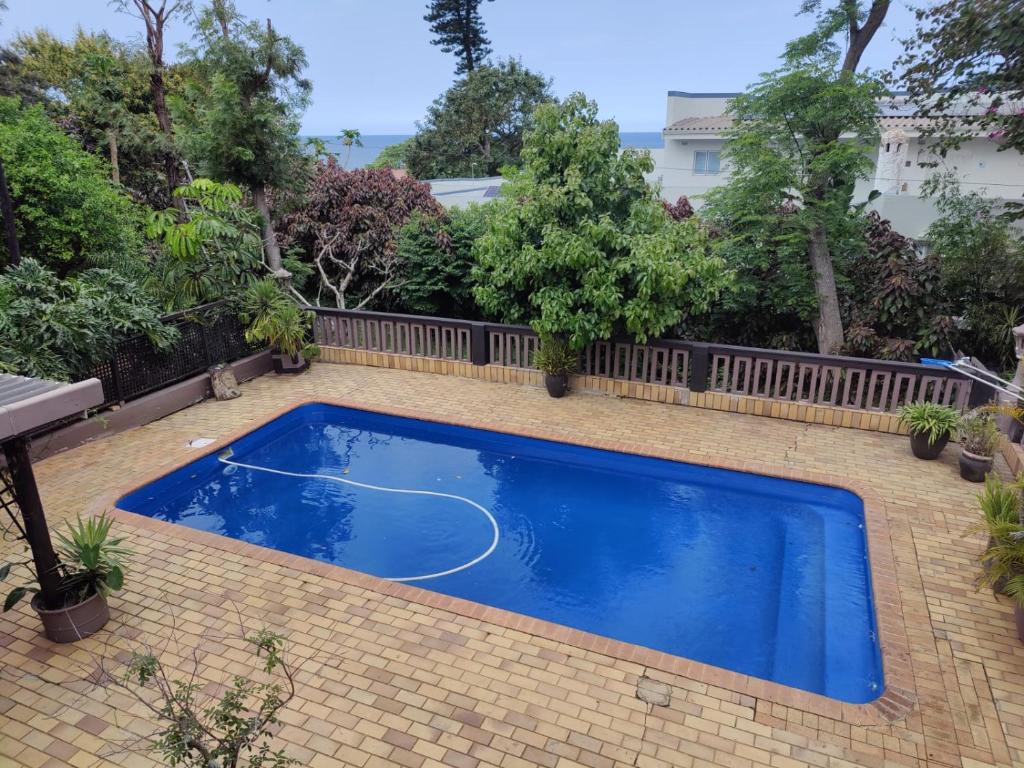 a blue swimming pool in a backyard with a fence at Upstairs Flat Sea Views Pet Friendly in Ballito