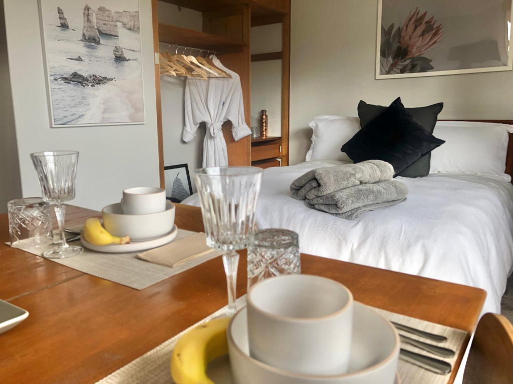 ローンセストンにあるLaunceston Lovely Vegan Homestayのベッド1台、テーブル、食器が備わる客室です。