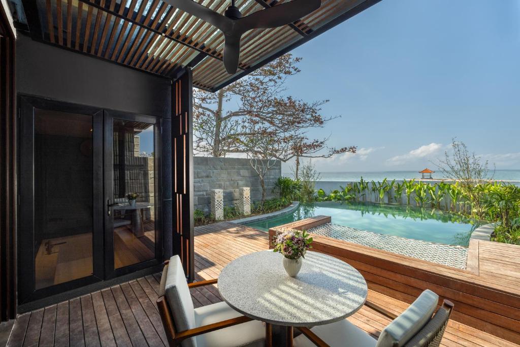 沙努爾的住宿－Sumitra Luxury Villas A Pramana Experience，一个带桌椅的庭院和一个游泳池