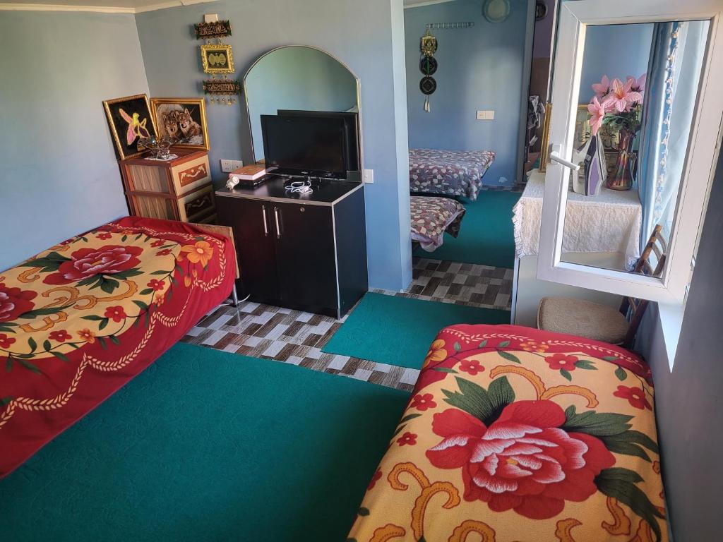 a small room with two beds and a television at Gabala Garden hostel in Gabala