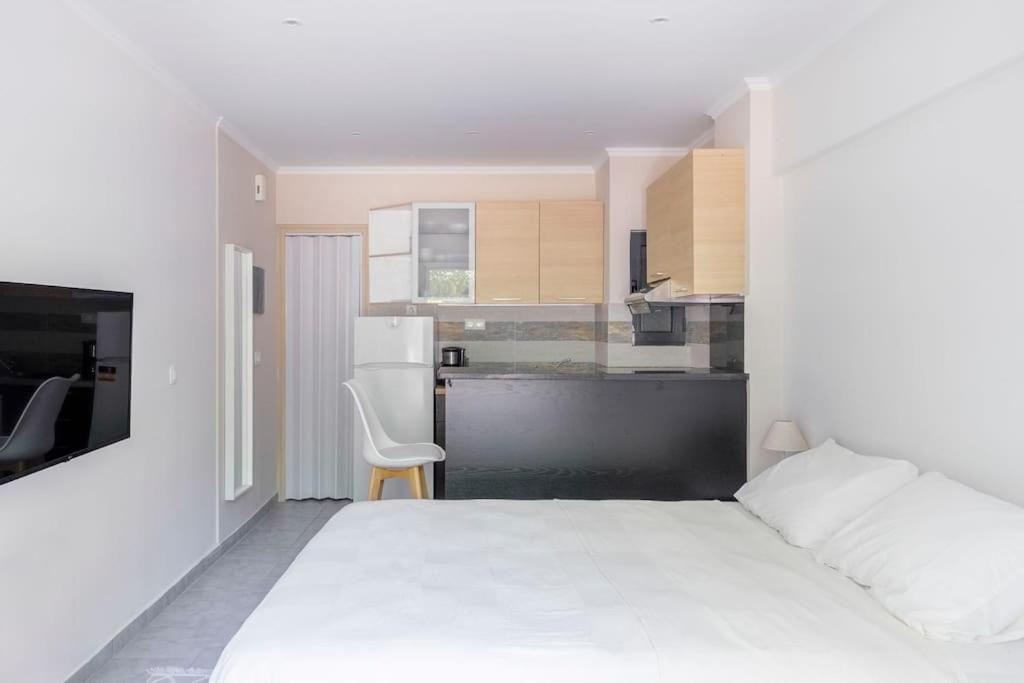 een slaapkamer met een wit bed en een keuken bij Voula's Secret Garden Studio in Athene