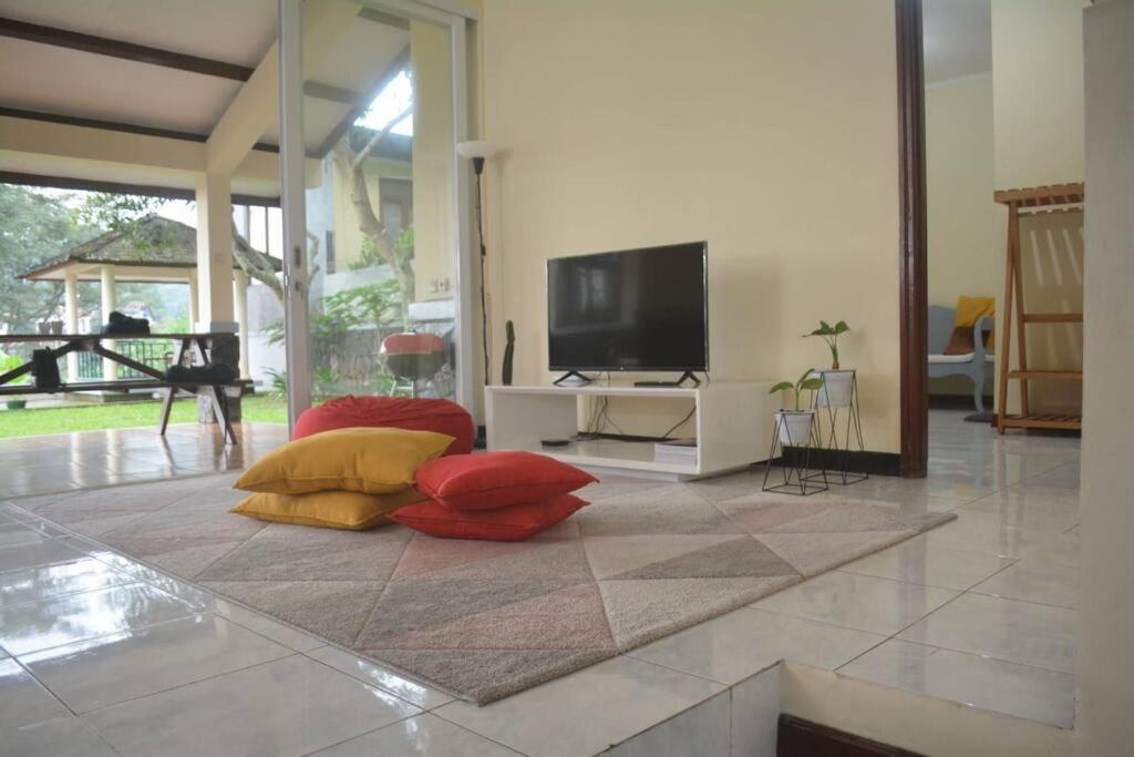 soggiorno con TV e cuscini rossi e gialli di Kuca Dago VII a Bandung