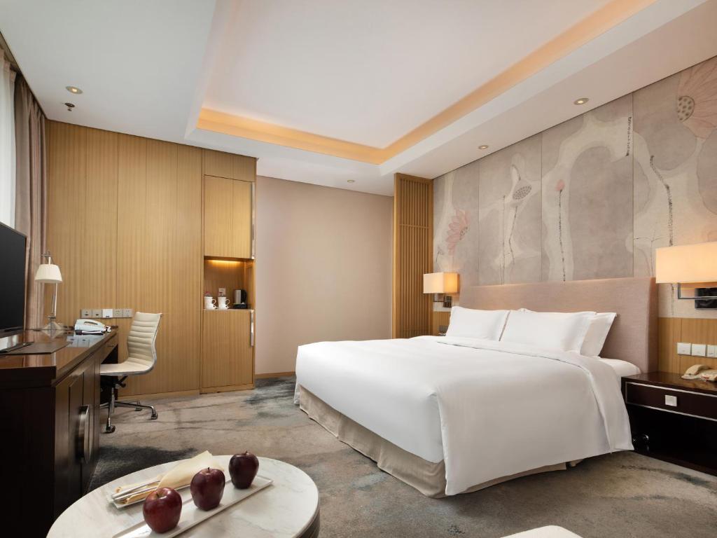 a bedroom with a large white bed and a desk at The Yun Hotel Hankou in Wuhan
