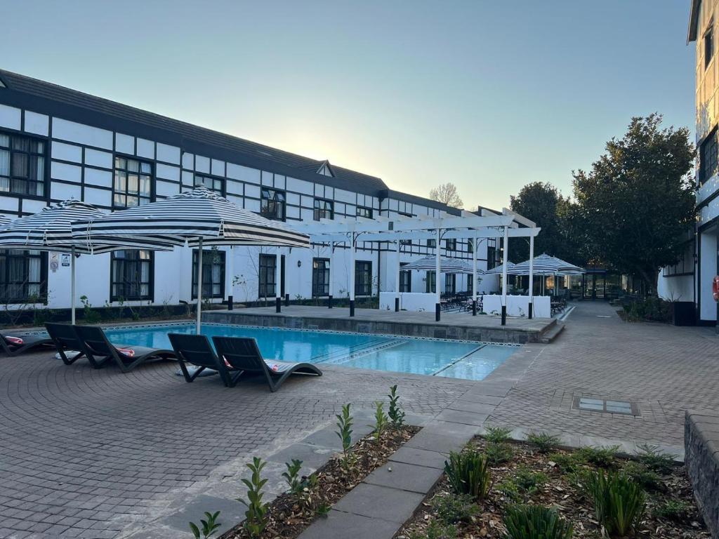 希爾頓的住宿－ANEW Hotel Hilton Pietermaritzburg，一座带游泳池的大型建筑,游泳池配有遮阳伞