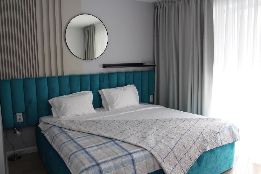 - une chambre avec un lit doté d'une tête de lit bleue et d'un miroir dans l'établissement Blue Apartment Mamaia Nord, à Mamaia